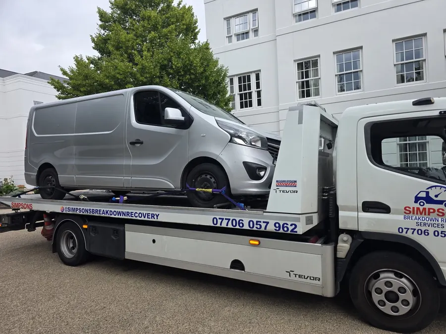 Silver Vauxhall Vivaro panel van strapped down on a Simpsons Breakdown Recovery flatbed truck in the West Midlands