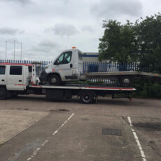 Delivery truck on back of a recovery truck